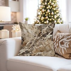 a living room with a christmas tree in the background and pillows on the couches