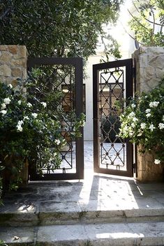 an open door leading to a garden with white flowers and greenery on either side