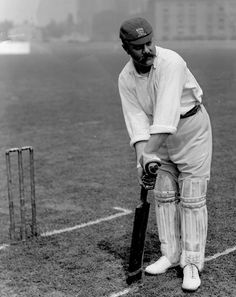 an old black and white photo of a man holding a bat on a baseball field