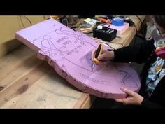 a young man is drawing on a piece of cardboard