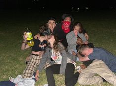 a group of people sitting on top of a grass covered field next to each other