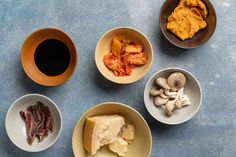 four bowls with different types of food in them on a blue countertop next to a cup of coffee