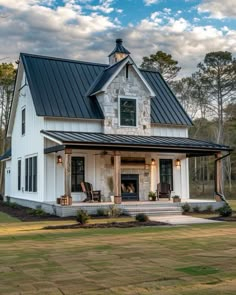 a white house with a black metal roof and two porches on the front lawn