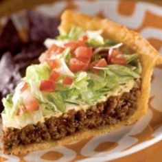 a piece of pie with lettuce and tomatoes on it sitting on a plate