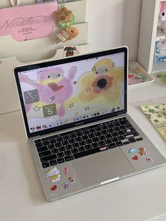 an open laptop computer sitting on top of a white desk next to stuffed animals and teddy bears