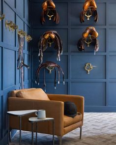 a living room with blue walls and leather furniture in the corner, two lamps hanging from the ceiling