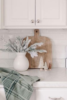 a kitchen counter with a cutting board on top of it and some plants in a vase