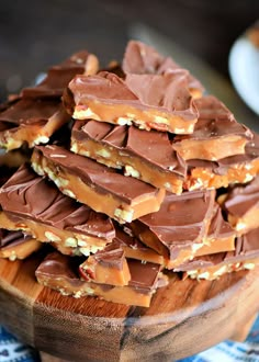 a wooden bowl filled with chocolate and peanut butter toffee bars on top of a table