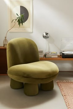 a green chair sitting on top of a white floor next to a table and lamp