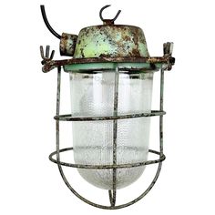 an old light hanging from the side of a metal cage with no lights on it