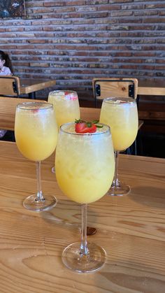 three glasses filled with drinks sitting on top of a wooden table