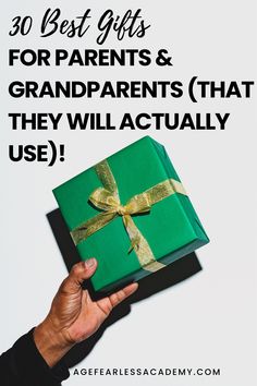 a person holding a green gift box with gold ribbon and the words, 30 best gifts for parents & grandparents that they will actually use