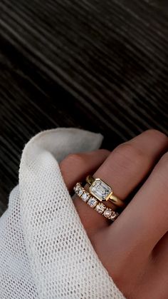 a woman's hand with two gold rings on top of it and one diamond in the middle