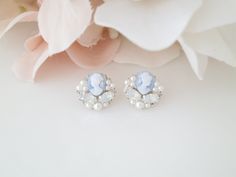 a pair of blue and white earrings sitting on top of a table next to flowers