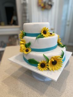 a three tiered cake with sunflowers on top