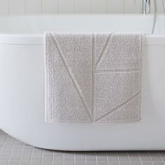 a bath tub with a towel hanging on the side of it's wall next to a tiled floor