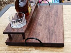 a wooden cutting board sitting on top of a table next to a glass and bottle