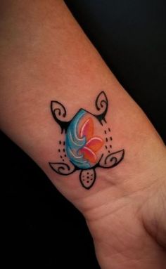 a small tattoo on the wrist of a woman's hand with an orange and blue design