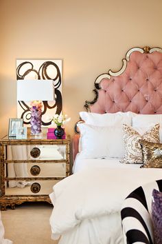 a bedroom with a pink headboard and white bedding, two nightstands on either side