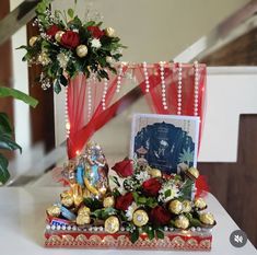 an arrangement of flowers, chocolates and decorations on a table with a photo frame