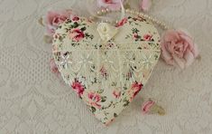 a heart shaped box sitting on top of a table next to pink roses and pearls