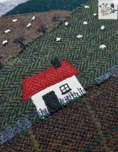 a close up of a knitted piece of cloth with a small house on it