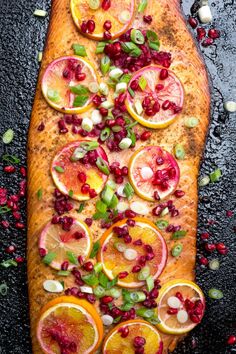 fish with pomegranate, oranges and herbs on it