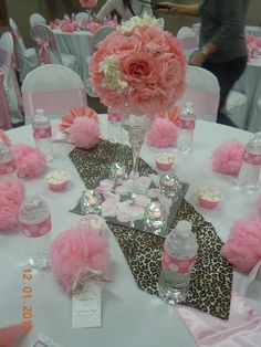 the table is set up with pink flowers and cupcakes on top of it