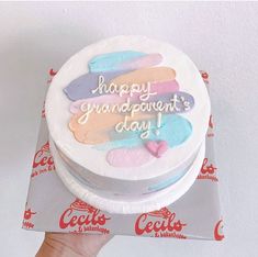 a hand holding up a cake with frosting on it that says happy grandparents day