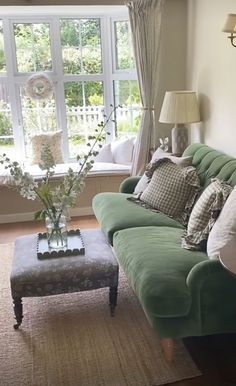 a living room with green couches and pillows in front of a large open window