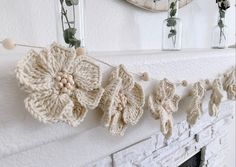 crocheted flowers are hanging on the mantle in front of a fireplace mantel