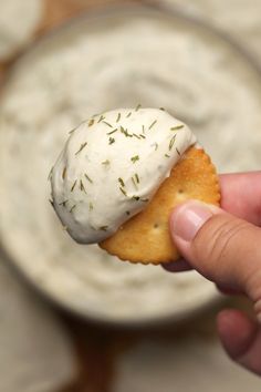 a hand holding a cracker with some kind of food in it's middle