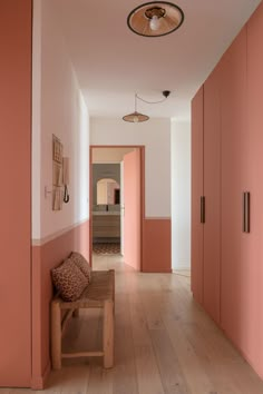 an empty hallway with pink walls and wooden floors