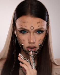 a woman with tattoos on her face and hands holding scissors in front of her face