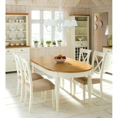 a dining room table with chairs and a bowl of fruit on top of the table