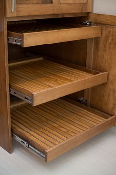 an open cabinet door with wooden shelves and drawers