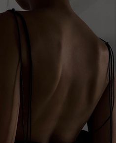 the back of a woman's body with no shirt on, wearing black jewelry