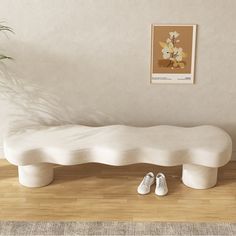 a white bench sitting on top of a wooden floor next to a potted plant