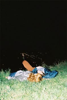 a person laying on the ground in grass