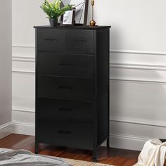 a black chest of drawers sitting on top of a wooden floor