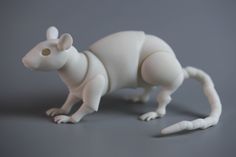 a white toy rat is standing on its hind legs