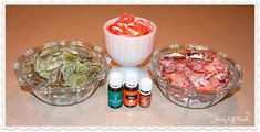 three bowls filled with different types of candies next to bottles of essentials on a table