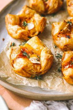 small pastries are sitting on a plate with wax paper and garnishes