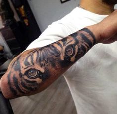 a man's arm with a tiger tattoo on it and an eyeball in the middle