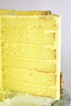 a piece of yellow cake sitting on top of a silver plate with a slice taken out of it