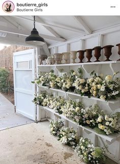 flowers and vases are arranged on shelves in the garage