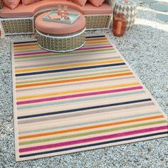 a striped rug is on the ground next to a couch and coffee table with pillows