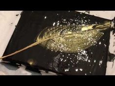 a leaf that is sitting on top of a piece of black and white paper with gold foil