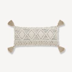 a white and beige pillow with tassels