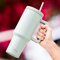 a person holding a white cup with a straw in it